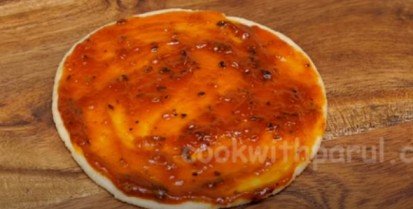 spreading pizza sauce on the pizza base for pizza recipe 