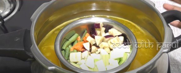 adding vegetable bowl in the cooler for sambar recipe 