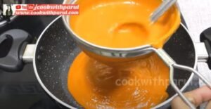 filtering tomato soup in a pan 